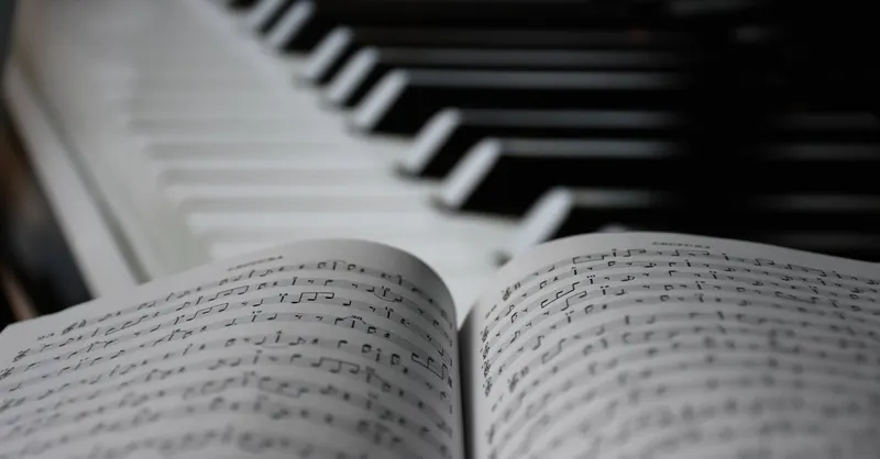 A focused view on sheet music with blurred piano keys in the background.