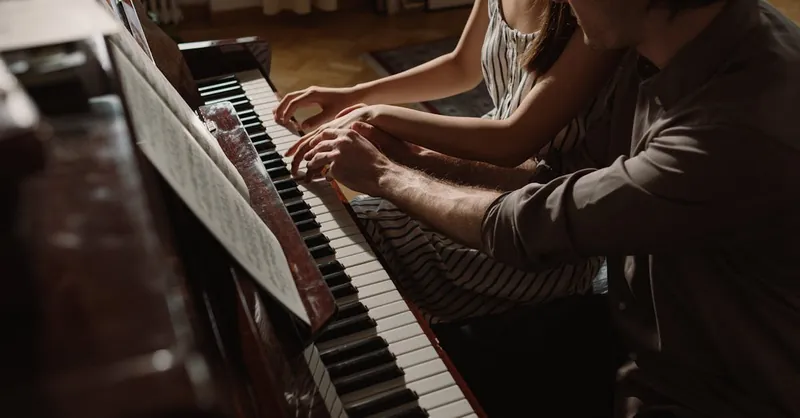 A couple playing piano together, showcasing musical collaboration and intimacy.