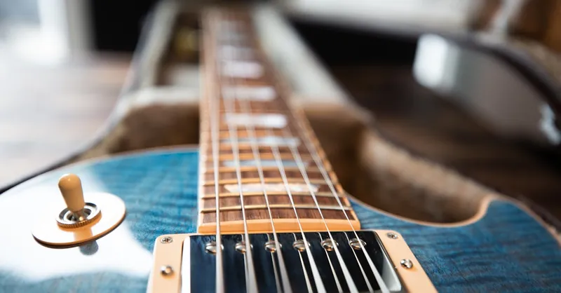 A detailed close-up of an electric guitar showing the strings and frets.