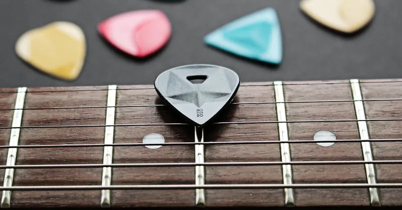 Detailed view of a guitar fretboard with colorful plectrums on a dark background.