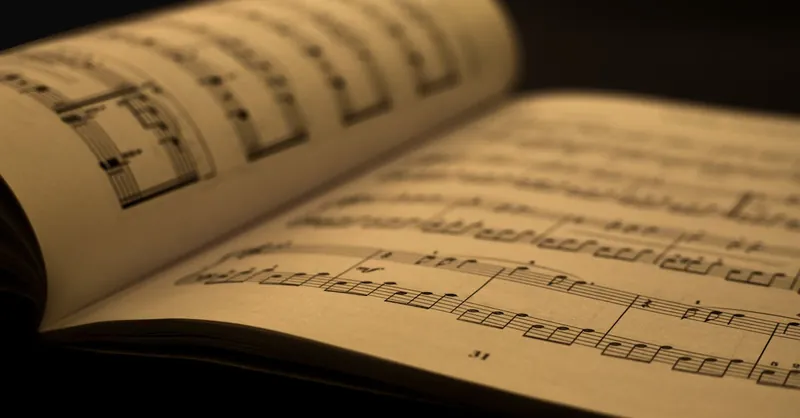 Detailed close-up of an open music sheet book, showcasing musical notes and composition in warm tones.