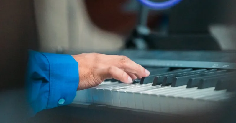 A close-up image of an adult hand playing the piano, showcasing musical skill and focus.