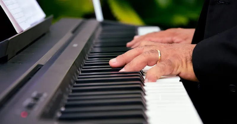 Hands playing a digital piano keyboard, capturing the essence of musical creativity.